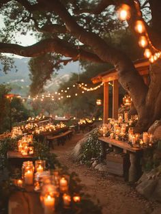 an outdoor dining area with candles and lights strung from the trees in front of it