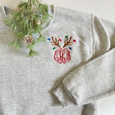 Our monogram reindeer sweatshirts are embroidered on our best selling crewneck sweatshirts. Choose your monogram font style. The design colors of the reindeer's antlers and lights will be as shown (light brown, light grey, red, kelly green, and royal blue) with a red monogram. PRODUCT DETAILS: Adult Unisex Sizes - 8 oz., pre-shrunk 50/50 cotton/polyester NuBlend® pill-resistant fleece High stitch density for a smooth printing canvas Seamless body with set-in sleeves 1x1 ribbed collar, cuffs and Christmas Shirt Embroidery Designs, Christmas Embroidery Sweatshirts, Monogram Clothes, Holiday Loungewear, Reindeer Lights, Charleston Wv, Christmas Pullover, Circle Font, Monogram Sweatshirt