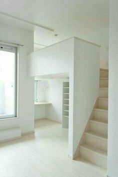 an empty room with white walls and stairs