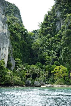 the water is crystal blue and clear with green trees on both sides, along with cliffs in the background