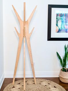 a wooden sculpture on the floor in front of a white wall and potted plant