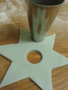 a star shaped object sitting on top of a wooden table next to a metal cup