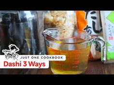 a glass measuring cup filled with liquid on top of a wooden table next to bags of food