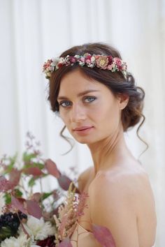 a woman with flowers in her hair is posing for the camera while holding a bouquet