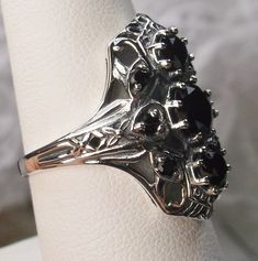 Black Cubic Zirconia Ring Description 9Gem Design#69 Made To Order Inspired by the Art Deco movement, I now offer this gorgeous Art Deco 1930s reproduction filigree ring in sterling silver. This ring is marked 925 for solid sterling. This lovely filigree ring is set with 3 central stunning center round cut Black CZ gemstones; 6mm center, 4mm top/bottom. 6 more round cut 2mm gemstones also grace the sides of the setting. Notice the beautiful design of the silver filigree setting and band. The rin Art Deco Oval Sapphire Ring With Prong Setting, Vintage Sapphire Ring With Diamond Cut, Oval Shape, Vintage Oval Sapphire Ring With Diamond Cut, Art Deco Sapphire Ring With Prong Setting, Collectible Art Deco Sapphire Ring, Art Deco Cluster Ring With 17 Jewels, Vintage White Gold Sapphire Ring For Formal Occasions, Formal Art Deco Cluster Ring, Vintage Silver Sapphire Ring With Diamond Cut