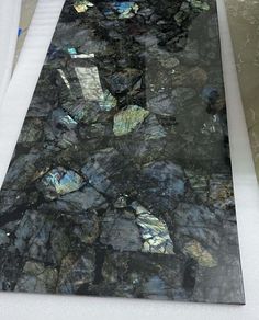 a counter top that is covered in black and blue marbles, with white trim around the edges