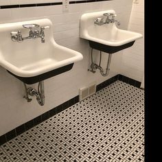 two white sinks sitting next to each other on a tiled wall in a public restroom