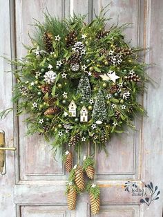 a wreath with pine cones and evergreens hanging on a door