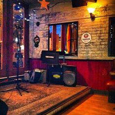 a room with a large rug, speakers and other items in front of a brick wall