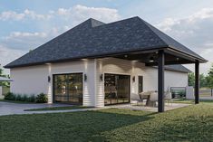 a white house with a black roof and covered patio in the middle of a grassy area