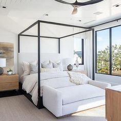 a bedroom with white furniture and large windows