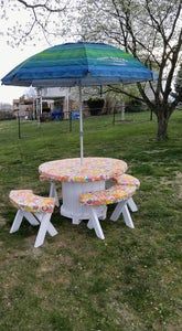 a picnic table with two benches under an umbrella