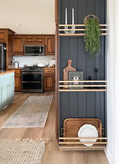 a kitchen with wooden shelves and white dishes on the counter top, next to a black wall