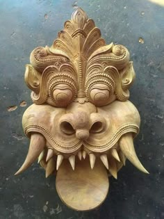 a wooden mask with large teeth on the ground