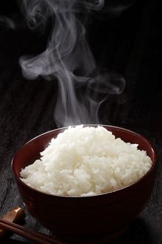 steaming rice in a bowl with chopsticks