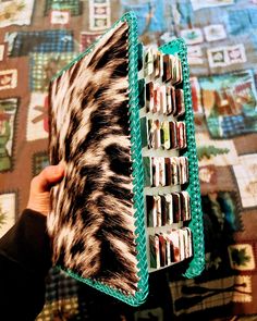 a person holding an animal print accordion on top of a quilted bed spreader