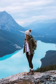 a woman standing on top of a mountain overlooking a lake