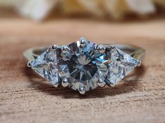 three stone diamond ring sitting on top of a wooden table