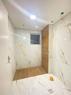 a bathroom with white marble walls and wood flooring, along with an open shower