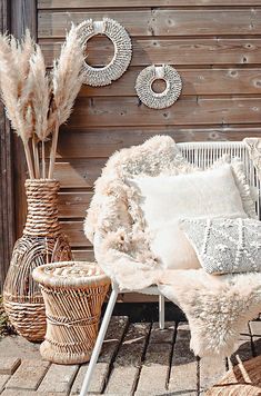 a white chair sitting next to a basket filled with pillows and other items in front of a wooden wall