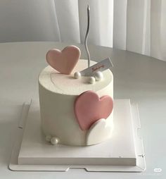 a white cake with pink hearts on top