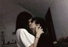 a man and woman kissing in the middle of a room with an open door behind them