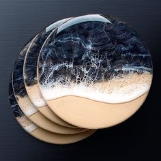 four coasters with blue and white designs on the top one has waves in it