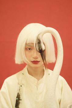 a woman with white hair is holding a bird on her head