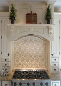 a stove top oven sitting inside of a kitchen next to white cupboards and drawers