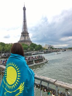 a woman is looking at the eiffel tower from across the river in paris