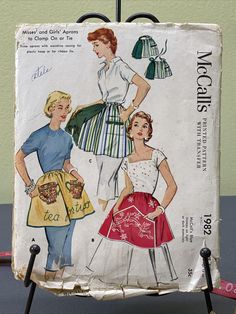 two women wearing aprons and dresses from the 1950's