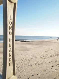 a bench sitting on top of a sandy beach next to the ocean with people walking in the distance