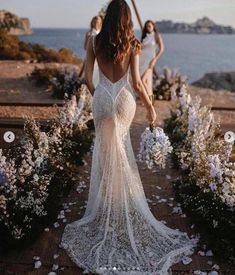 the back of a woman's dress as she walks down a path with flowers