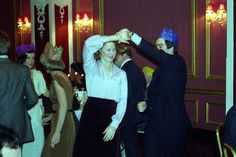 two people in formal wear dancing together at a party with other people standing and sitting around