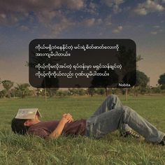 a man laying in the grass with a book on his head and an advertisement above him