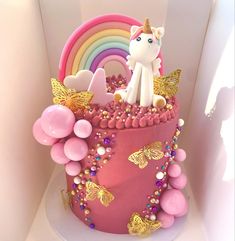 there is a pink cake with a unicorn on top and balloons around the edges,