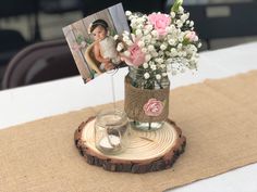 a vase filled with flowers sitting on top of a wooden table next to a photo