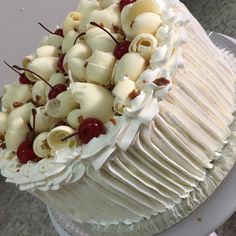 a close up of a cake with white frosting and cherries on the top