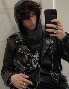 a man in a leather jacket taking a selfie with his cell phone while wearing a hoodie