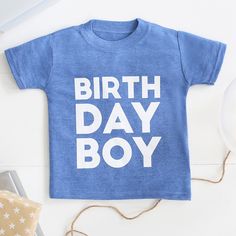 a blue shirt with the words birth day boy on it sitting next to other items