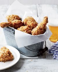 some fried food is in a bucket next to a glass of beer and napkins