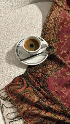 a cup of coffee sitting on top of a saucer next to a red rug