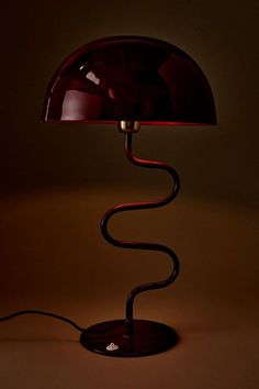 a red table lamp with a black base on a brown background, lit by a dim light