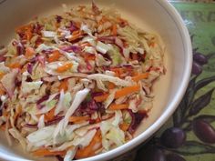 a bowl filled with coleslaw and carrots on top of a green table