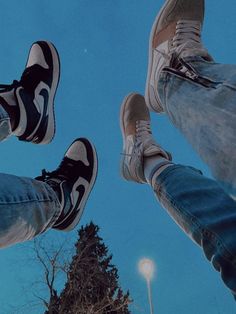 two people standing in the air with their feet up and one person wearing blue jeans