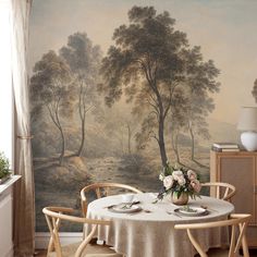 a dining room with a table and chairs in front of a painting on the wall