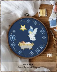 a cross - stitch pattern with an angel and sheep in the middle, surrounded by thread spools