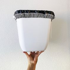 a person holding up a white vase with black and white stripes on it's sides