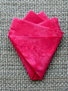 three pink napkins folded on top of each other in the shape of a heart