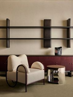 a living room with two chairs, a table and some bookshelves on the wall